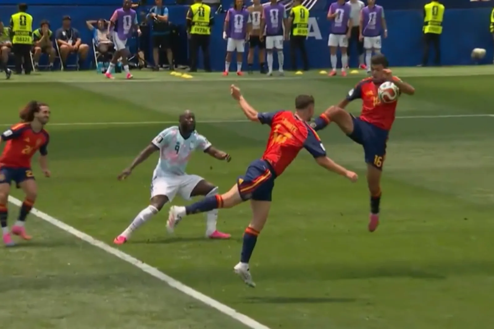 Jugadores de España y Bélgica disputando un balón en el aire durante un partido, con el árbitro al fondo