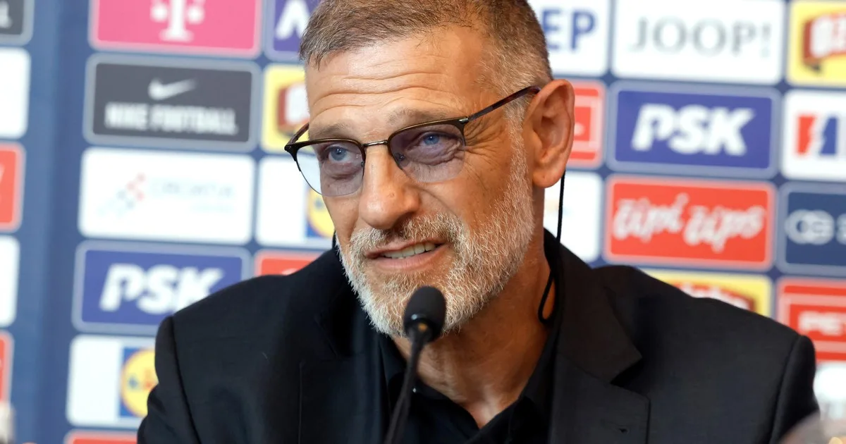 Slaven Bilic sonriente en conferencia de prensa con la camiseta de Croacia de fondo
